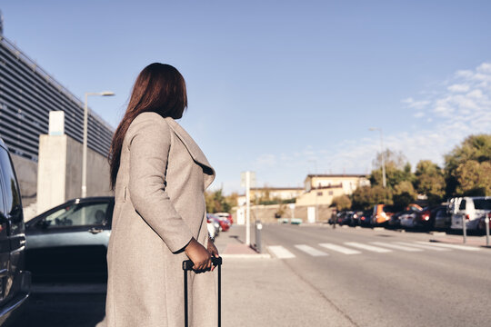 detail of the lower part of a businesswoman with hand luggage waiting for a vehicle on the motorway