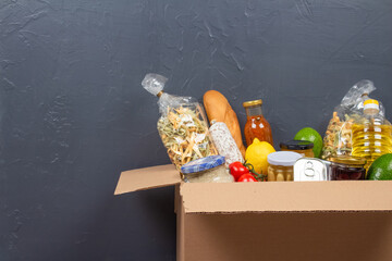 Closeup view of donation box with different food donations on gray wall background with copy space...