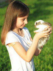Little girl hugs a rabbit. Friendship and care of animals. Easter symbol