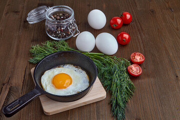 Fried chicken egg in a small frying pan with a stand, a bunch of dill