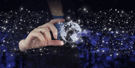 Global world telecommunication network. Hand hold digital hologram world, earth, map, globe sign on city dark blurred background. International business concept.