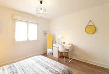 Bedroom with black and white bed and white desk. Wall mirror.