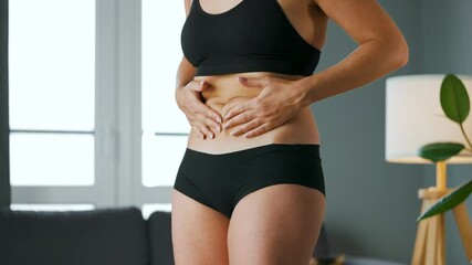 Woman compressing the skin on her stomach and sides checking for cellulite and excess subcutaneous fat