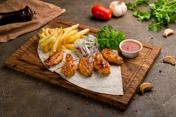 chicken wings in barbecue sauce with french fries, onion and tomato sauce