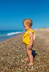 Fototapeta na wymiar Baby is sitting on the beach by the sea. Selective focus.