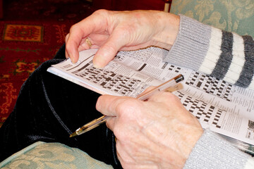 Senior elderly person keeping mind active by doing crossword puzzle