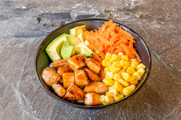 Poke bowl with ripe avocado, yakisoba chicken, sweet corn and grated carrot