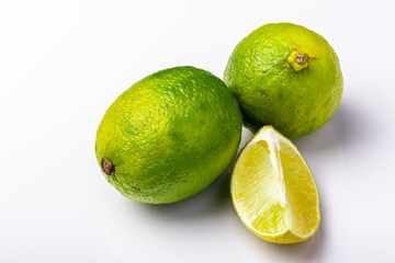 two whole and one cut limes on white background