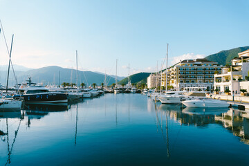 Fototapeta na wymiar Yachts at the pier against the backdrop of coastal hotels in Porto Montenegro