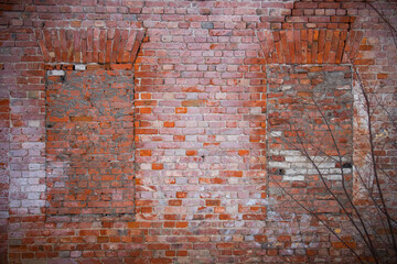 Old shabby red brick wall with bricked up windows