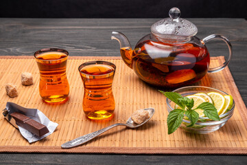 tea with mint and lime in a glass tea-pot and glasses with a bar  of chocolate