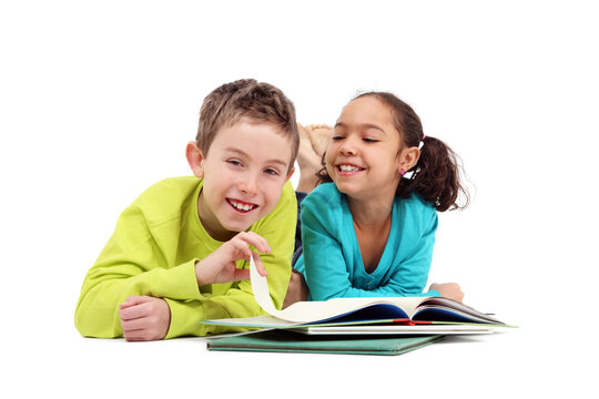 Two Grade School Children Reading A Book Laying Down