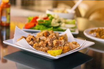 fried pork crackling,
traditional Brazilian recipe for pork crackling on a table with salad and a portion of rice in the background