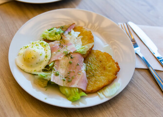 Traditional Belarusian draniki served with ham, fried egg and fresh vegetables