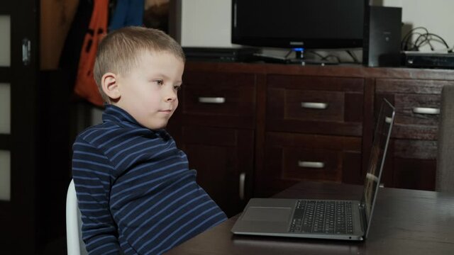 A five-year-old boy watches a cartoon on a computer
