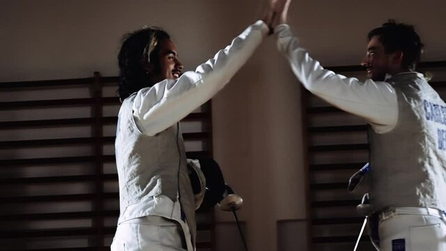 Smiling Young Men In Fencing Gear Hi-Fiving Each Other