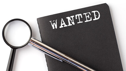 WANTED - business concept, magnifier with white text message on black notebook
