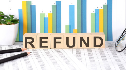 REFUND word written on the wood block with chart, glasses and pencils