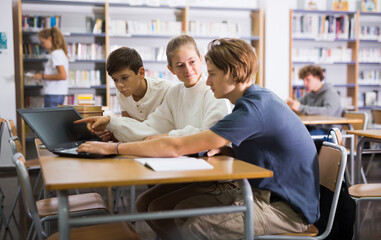 Teenage students working in groups in college library