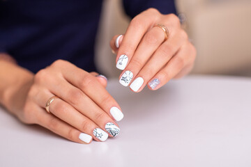 Beautiful female hands with fashion manicure nails, white and silver gel polish, stars design