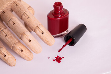 Wooden hand near red gel polish. Manicure and nail care concept.