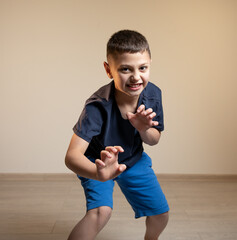 a boy in a blue t-shirt growls and holds his hands in front of him, depicts a tiger