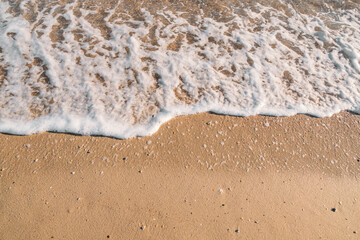 Top view of coastline. Tide of wave. Wave foam. Golden sea sand