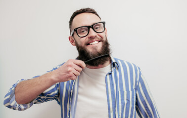 Professional beard care. Handsome bearded man with hairbrush combing his beard. Close-up