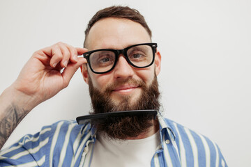 Professional beard care. Handsome bearded man with hairbrush combing his beard. Close-up