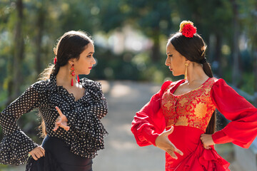 Two woman in flamenco dress dancing in a park - obrazy, fototapety, plakaty