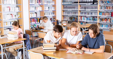 Three schoolchildren, preparing for lessons in the school library, writes synopsis in an exercise...