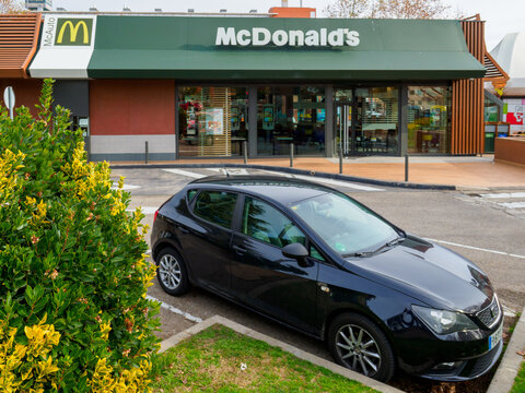 ALCALA DE HENARES, SPAIN; JANUARY 2, 2022: BLACK CAR PARKED IN FRONT OF A MCDONALDS, WITH MCAUTO