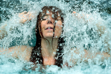 beautiful young cute sexy redhead woman under the splashing falling water shower waterfall in the Spa Wellness pool