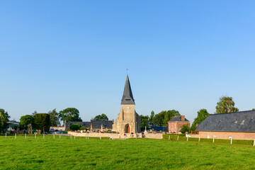 Fototapeta na wymiar Church in front of a field in the traditional French village of Saint Sylvain in Europe, France, Normandy, Seine Maritime, in summer on a sunny day.