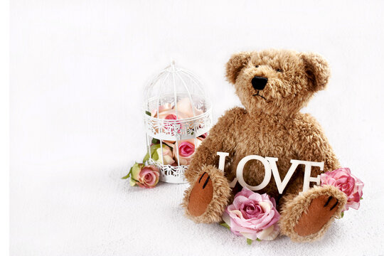 Cute teddy bear with with roses and LOVE inscription sitting on white background with empty copy space - Powered by Adobe