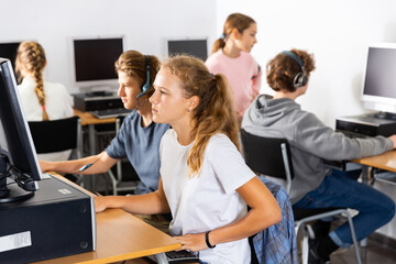 Fototapeta premium Fifteen-year-old schoolgirl, studying at school in an informatics lesson in the classroom, sitting at the computer