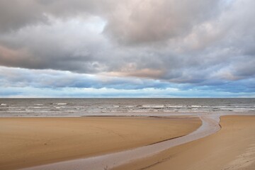 Baltic sea shore at sunset. View from the beach (sand dunes). Dramatic sunset sky, glowing clouds....