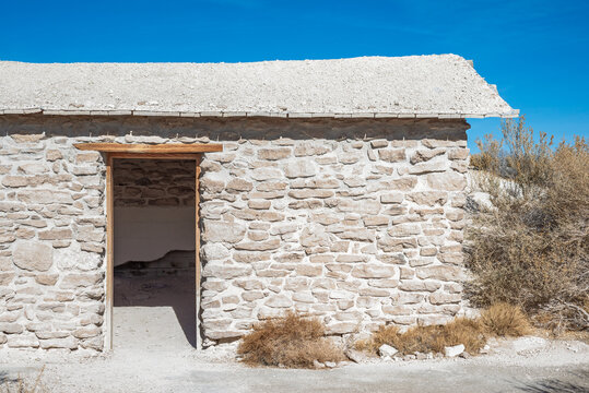 Longstreet Cabin is a white building constructed from the nearby alkali rocks and light colored soils. It has rough stonework and a natural roof. Ash Meadows National Wildlife Refuge, Nye County, NV