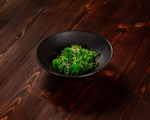 Chuka seaweed salad with sesame seeds in a plate on a dark wood background