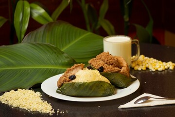 Foto de dos quimbolitos de vainilla y chocolate en plato blanco, acompañado de taza de leche