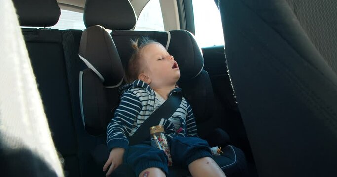 cute baby toddler girl is sleeping on rear setas of vehicle during the travel. Carefree childhood watching dreams on road in the car
