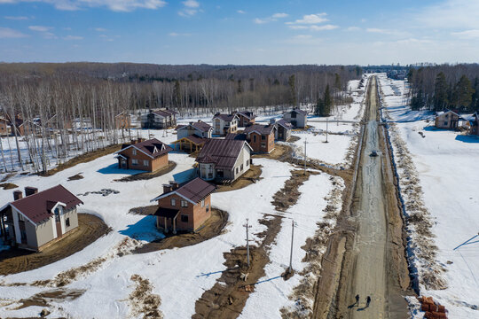Aerial view of a dirt road in a cottage settlement under construction in the forest in Siberia in spring