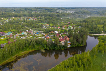Aerial view of a cottage village on the bank of a river on the edge of an endless forest in Siberia