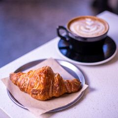 Hot coffee and croissants on a marble table.