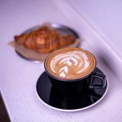 Hot coffee and croissants on a marble table.