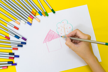 Close up of kid hands drawing with Colorful stationary school supplies on white trending background with copyspace or text flat lay. Colorful Education or back to school Concept
