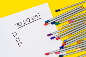 Colorful stationary school supplies with on yellow trending background with to do list copyspace or text flat lay. Colorful Education or back to school Concept