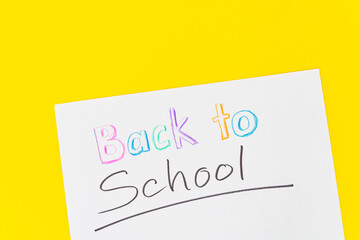 Colorful stationary school supplies with crayon text "Back to School" on yellow trending background with copyspace or text flat lay. Colorful Education or back to school Concept
