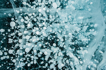 Texture of beautiful blue ice with cracks and air bubbles in the frozen lake. Winter nature background. 