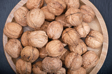 Group of walnuts on a black background. Nuts on a wooden plate. Walnut on black top view.